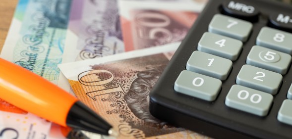 British bank notes next to a calculator and pen