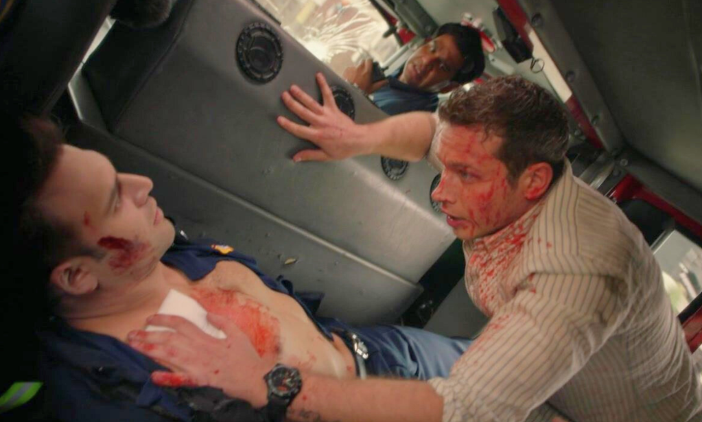 Buck tending to Eddie's gunshot wound in the back of a fire engine.