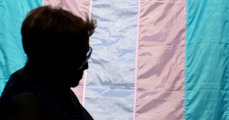 A silhouette in front of a trans flag.