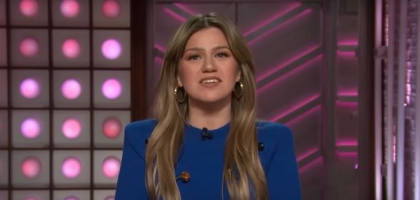 Kelly Clarkson addressing the camera on her talk show, wearing a blue jumper.