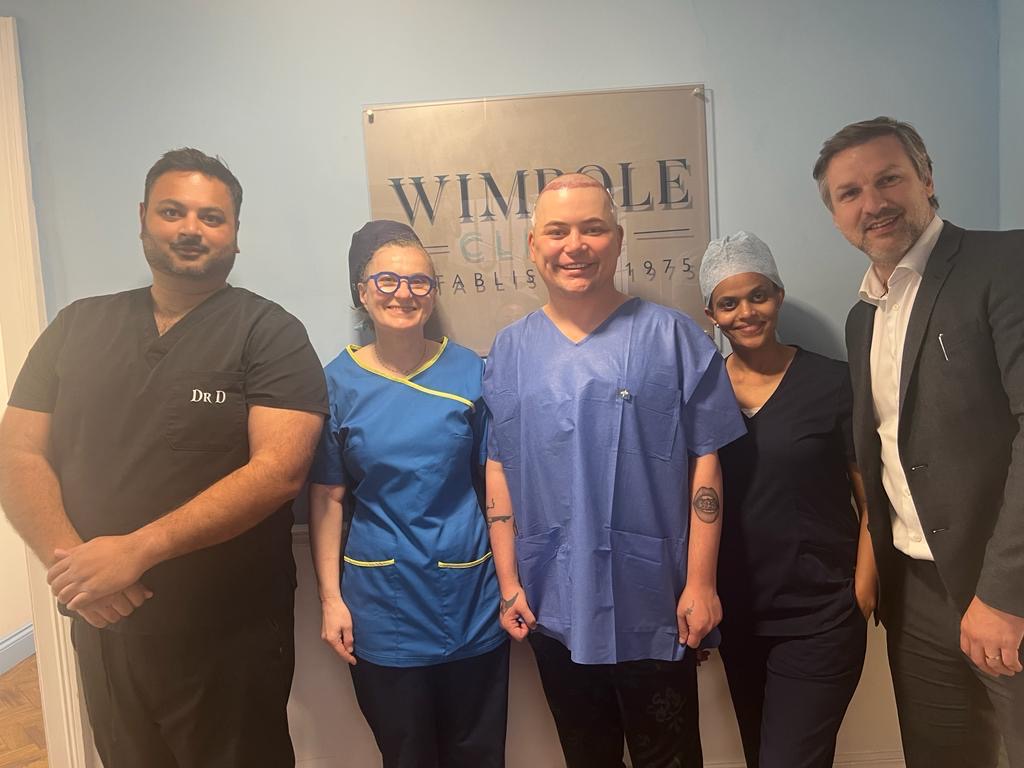 Baga Chipz stands with Wimpole Clinic staff after having a hair transplant. 