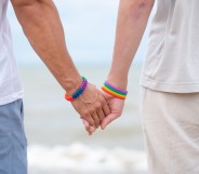 Back view gay couple holding hands at the beach.