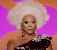 A still of RuPaul smiling watching a lip-sync in episode six of Drag Race season 17