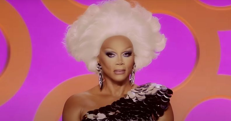 A still of RuPaul smiling watching a lip-sync in episode six of Drag Race season 17