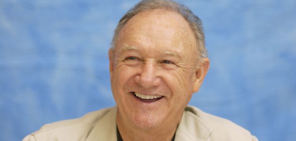 The Birdcage star Gene Hackman smiling against a blue background.