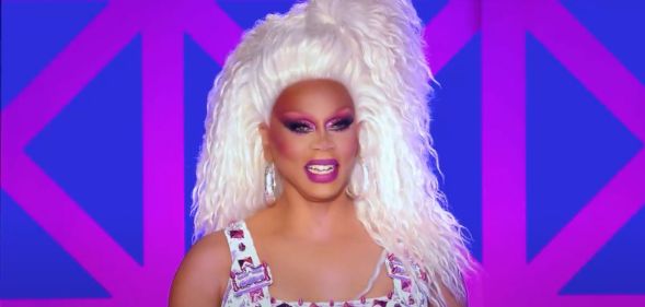 A still of RuPaul smiling during a performance on Drag Race UK season 3