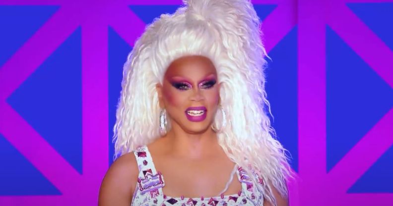 A still of RuPaul smiling during a performance on Drag Race UK season 3