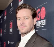 Armie Hammer on a red carpet in 2019 looking at the camera side ways on.