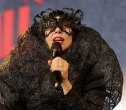 Lady Gaga performs in a lace black outfit holding a microphone.