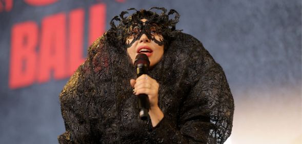 Lady Gaga performs in a lace black outfit holding a microphone.