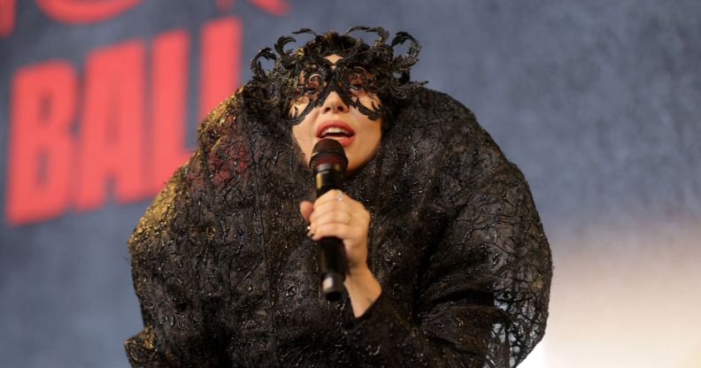 Lady Gaga performs in a lace black outfit holding a microphone.