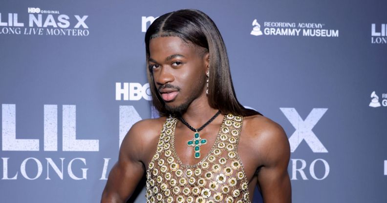 Lil Nas X poses on a red carpet in 2024.