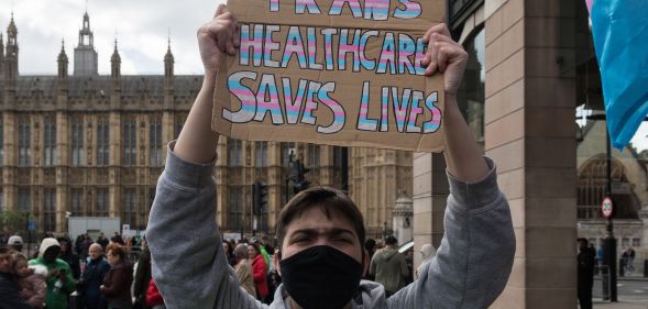 A person holds a sign reading "trans healthcare saves lives."