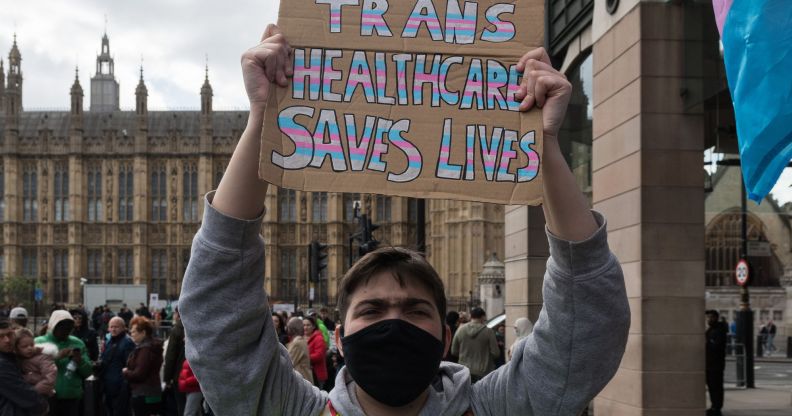 A person holds a sign reading "trans healthcare saves lives."