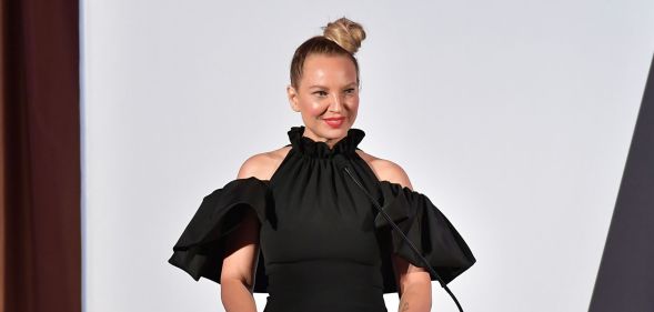 Singer Sia on a stage in a black dress smiling