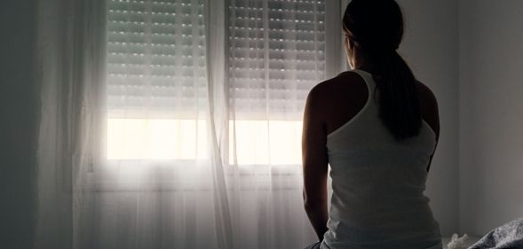 Stock image of a domestic abuse victim sitting with their back to the camera