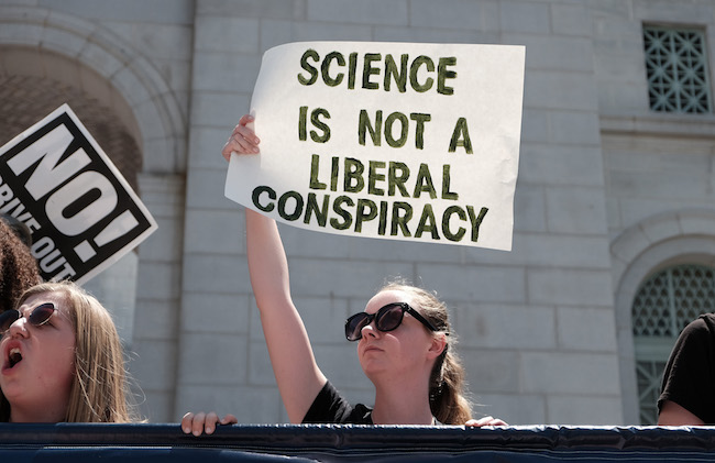 A protester at the March for Science holds up a sign reading 'science is not a liberal conspiracy'