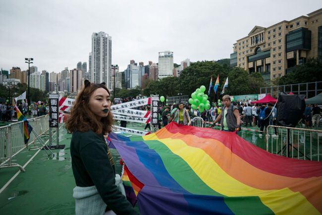 A participant of Hong Kong's annual pride parade stands next to a large rainbow flag on November 26, 2016.  A huge rainbow flag led thousands through the streets of Hong Kong on November 26 as the city's LGBT community braved the rain and wind to call for equality at its annual pride parade. / AFP / Aaron TAM        (Photo credit should read AARON TAM/AFP/Getty Images)