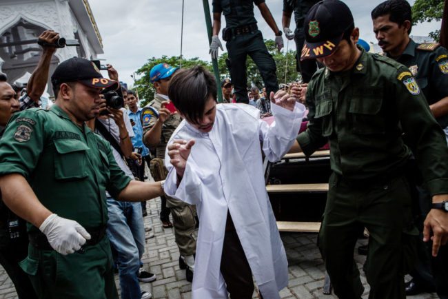 BANDA ACEH, INDONESIA - MAY 23: An indonesian man escorted by the sharia police after get caning in public from an executor known as 'algojo' for having gay sex, which is against Sharia law at Syuhada mosque on May 23, 2017 in Banda Aceh, Indonesia. The two young gay men, aged 20 and 23, were caned 85 times each in the Indonesian province of Aceh during a public ceremony after being caught having sex last week. It was the first time gay men have been caned under Sharia law as gay sex is not illegal in most of Indonesia except for Aceh, which is the only province which exercises Islamic law. The punishment came a day after the police arrested 141 men at a sauna in the capital Jakarta on Monday due to suspicion of having a gay sex party, the latest crackdown on homosexuality in the country. (Photo by Ulet Ifansasti/Getty Images)