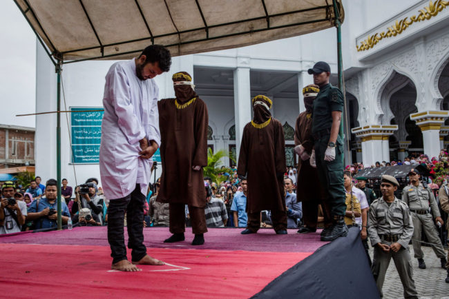 BANDA ACEH, INDONESIA - MAY 23: An Indonesian man gets caning in public from an executor known as 'algojo' for having gay sex, which is against Sharia law on May 23, 2017 in Banda Aceh, Indonesia. The two young gay men, aged 20 and 23, were caned 85 times each in the Indonesian province of Aceh during a public ceremony after being caught having sex last week. It was the first time gay men have been caned under Sharia law as gay sex is not illegal in most of Indonesia except for Aceh, which is the only province which exercises Islamic law. The punishment came a day after the police arrested 141 men at a sauna in the capital Jakarta on Monday due to suspicion of having a gay sex party, the latest crackdown on homosexuality in the country. (Photo by Ulet Ifansasti/Getty Images)