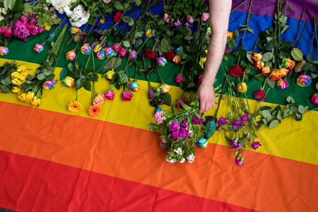 Demonstrators in London lay roses on a rainbow flag as they protest purge of gay men in Chechnya