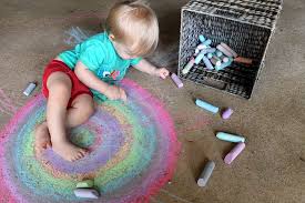 A small child draws a rainbow on the pavement