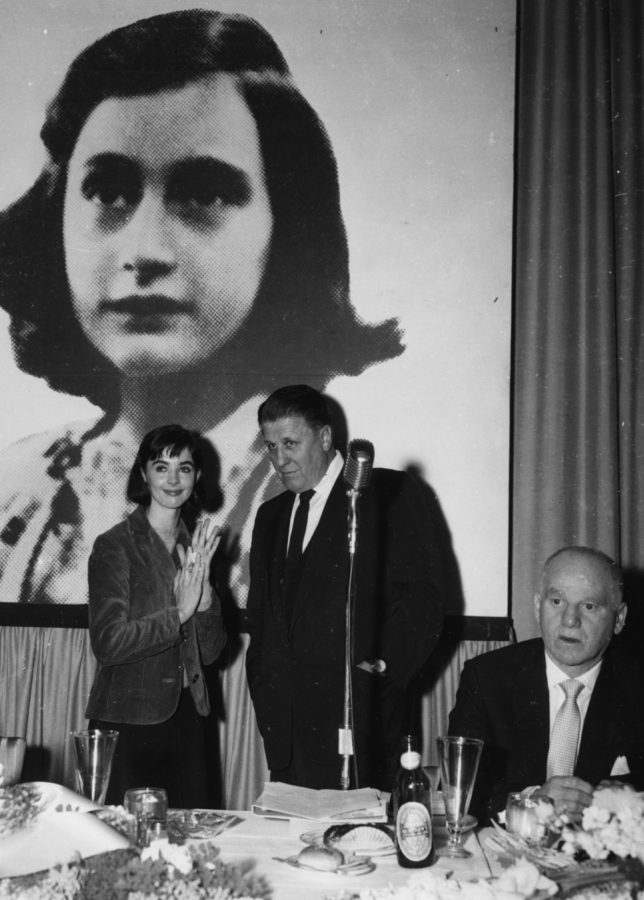 Actress Millie Perkins talking to producer George Stevens in front of a picture of holocaust victim Anne Frank, at a reception for their film 'The Diary of Anne Frank' at 20th Century Fox Studios in Hollywood, February 27th 1958. (Photo by Keystone/Hulton Archive/Getty Images)