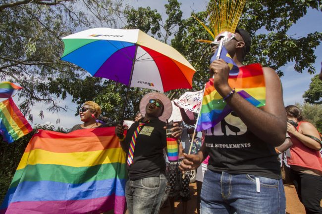 People holding rainbow flags and umbrellas take part in the Gay Pride parade in Entebbe on August 8, 2015. Ugandan activists gathered for a gay pride rally, celebrating one year since the overturning of a strict anti-homosexuality law but fearing more tough legislation may be on its way. Homosexuality remains illegal in Uganda, punishable by a jail sentence. AFP PHOTO/ ISAAC KASAMANI        (Photo credit should read ISAAC KASAMANI/AFP/Getty Images)