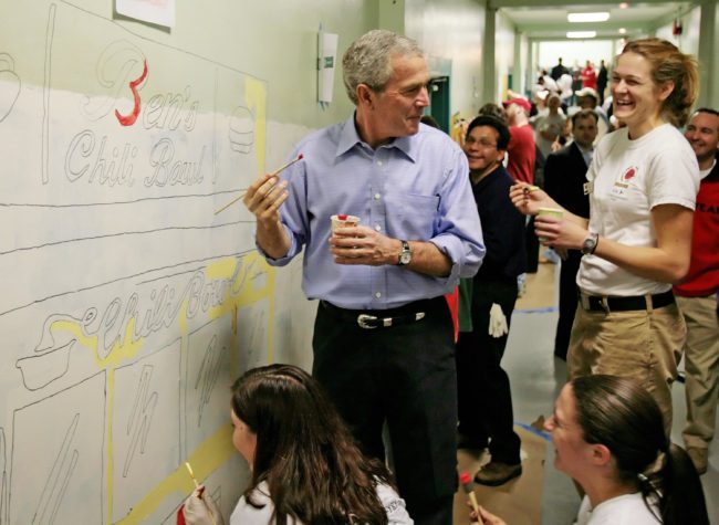 Washington, UNITED STATES: US President George W. Bush (C) and US Attorney General Alberto Gonzales (3rd R) joke with City Year volunteers as they paint a mural at Cordozo High School in Washington, DC, 15 January 2007. President Bush made a surprise visit to the school for the Martin Luther King Jr. holiday. AFP PHOTO/Jim WATSON (Photo credit should read JIM WATSON/AFP/Getty Images)