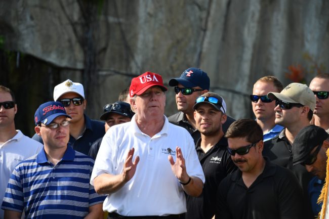 US President Donald Trump speaks to service members of the United States Coast Guard during an invitation to play golf at Trump International Golf Course in Mar-a-Lago, Florida on December 29, 2017. The President invited members of the Coast Guard to play golf to thank them personally for their service of patrolling the waters near Palm Beach and Mar-a-Lago. / AFP PHOTO / Nicholas Kamm (Photo credit should read NICHOLAS KAMM/AFP/Getty Images)