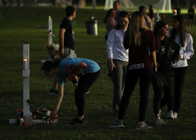 PARKLAND, FL - FEBRUARY 16:  Students gather around a memorial cross that honors victims of the mass shooting at Marjory Stoneman Douglas High School, at Pine Trail Park on February 16, 2018 in Parkland, Florida. Police arrested 19 year old former student Nikolas Cruz for killing 17 people at the high school.  (Photo by Mark Wilson/Getty Images)
