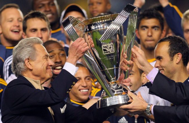 CARSON, CA - NOVEMBER 20:  Landon Donovan #10 of the Los Angeles Galaxy (R) receives the Philip F. Anschutz Trophy from Philip F. Anschutz on the podium after the Los Angeles Galaxy defeated the Houston Dynamo in the 2011 MLS Cup at The Home Depot Center on November 20, 2011 in Carson, California. The Galaxy defeated the Dynamo 1-0 to win the 2011 MLS Cup.  (Photo by Victor Decolongon/Getty Images)