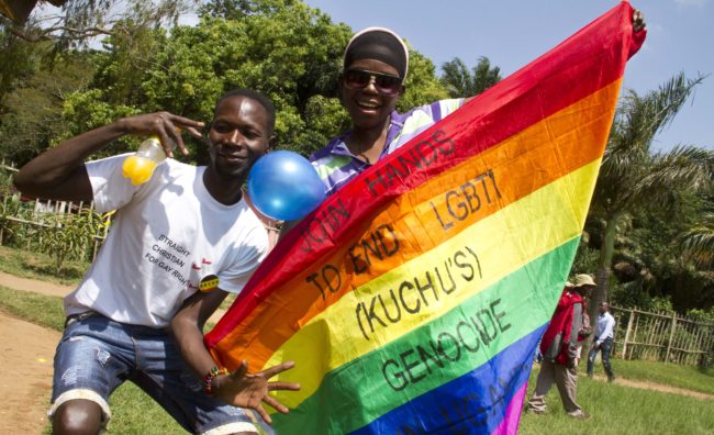 Ugandan men hold a rainbow flag reading "Join hands to end LGBTI (Lesbian Gay Bi Trans Intersex - called Kuchu in Uganda) genocide" as they celebrate on August 9, 2014 during the annual gay pride in Entebbe, Uganda. Uganda's attorney general has filed an appeal against the constitutional court's decision to overturn tough new anti-gay laws, his deputy said on August 9. Branded draconian and "abominable" by rights groups but popular domestically, the six-month old law which ruled that homosexuals would be jailed for life was scrapped on a technicality by the constitutional court on August 1. AFP PHOTO/ ISAAC KASAMANI        (Photo credit should read ISAAC KASAMANI/AFP/Getty Images)