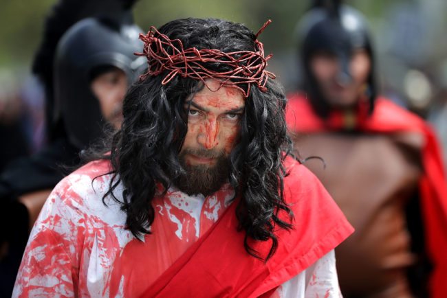 LANGLEY PARK, MD - APRIL 14: Surrounded by observers and actors playing Roman soldiers, Henry Colindres (C) portrays Jesus during a traditional Via Crucis, or Way of the Cross, procession on the Christian Good Friday holiday April 14, 2017 in Langley Park, Maryland. The recreation of the crucifixion of Jesus drew several thousand area Catholics and marched its way through several Maryland neighborhoods in the suburbs of the nation's capital. (Photo by Chip Somodevilla/Getty Images)