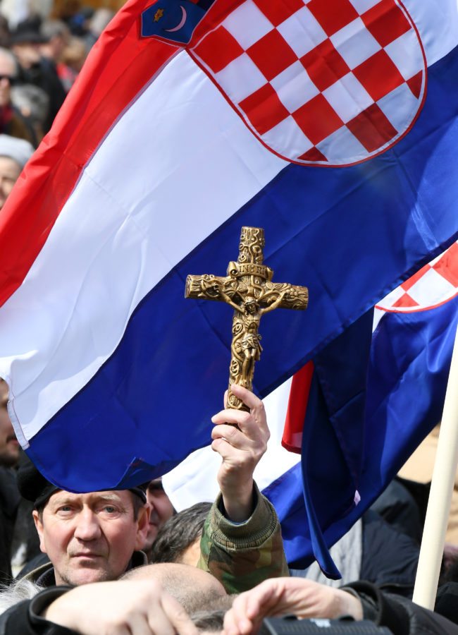 A man holds a cross as opponents to a treaty safeguarding women, backed by the Roman Catholic Church, protest against its ratification arguing it is imposing what they call a "gender ideology" in the Croatian capital, Zagreb, on March 24, 2018. Protestors against the Council of Europe convention on preventing and combating violence against women and domestic violence (Istanbul Convention) -- the world's first binding instrument to prevent and combat violence, from marital rape to female genital mutilation -- hold banners against its ratification, an issue that has split the Balkan country. / AFP PHOTO / STR (Photo credit should read STR/AFP/Getty Images)