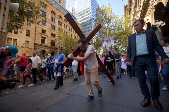 24-year-old student Alec Green, depicting himself as Jesus Christ, carries a cross in a re-enactment from the Bible on Good Friday in Sydney on March 30, 2018. Good Friday, part of the Easter weekend, is a Christian religious holiday commemorating the crucifixion of Jesus Christ and his death and is a public holiday throughout Australia. / AFP PHOTO / Peter PARKS (Photo credit should read PETER PARKS/AFP/Getty Images)