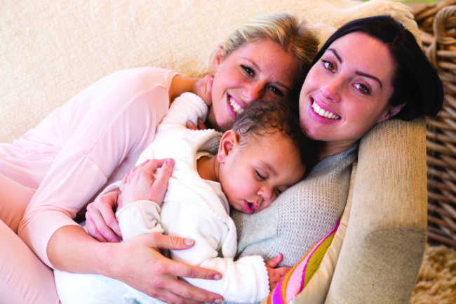 Same sex female couple lying down with their baby son