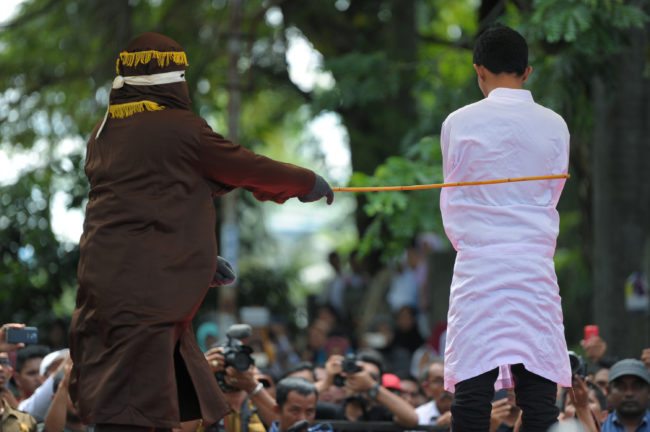 A religious officer canes an Acehnese man (R) 100 times for having sex outside marriage, which is against sharia law, in Banda Aceh on November 28, 2016. Aceh is the only province in the world's most populous Muslim-majority country that imposes sharia law. People can face floggings for a range of offences -- from gambling, to drinking alcohol, to gay sex. / AFP / Chaideer MAHYUDDIN (Photo credit should read CHAIDEER MAHYUDDIN/AFP/Getty Images)