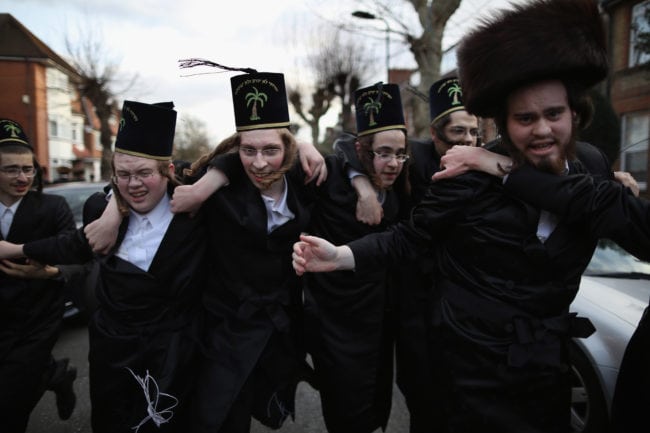 LONDON, ENGLAND - MARCH 05: A group of Orthodox Jewish boys dance in the street before going into the home of a local businessmen while collecting money during the Jewish holiday of Purim on March 5, 2015 in London, England. The annual Purim holiday is celebrated by Jewish communities around the world with parades and costume parties. The Biblical Book of Esther recorded the deliverance of the Jewish people from a plot to exterminate them in the ancient Persian empire 2,500 years ago and continues to be celebrated today. (Photo by Dan Kitwood/Getty Images)
