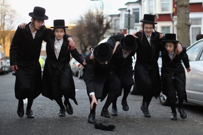 LONDON, ENGLAND - MARCH 05: A group of Orthodox Jewish boys dance in the street before going into the home of a local businessmen while collecting money for their school during the Jewish holiday of Purim on March 5, 2015 in London, England. The annual Purim holiday is celebrated by Jewish communities around the world with parades and costume parties. The Biblical Book of Esther recorded the deliverance of the Jewish people from a plot to exterminate them in the ancient Persian empire 2,500 years ago and continues to be celebrated today. (Photo by Dan Kitwood/Getty Images)