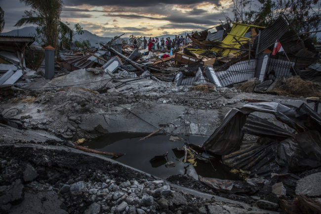 PALU, INDONESIA - OCTOBER 05: People standing at a damaged area after being hit by liquefaction in Petobo village following the earthquake on October 5, 2018 in Palu, Central Sulawesi. The death toll from last weeks earthquake and tsunami has risen to at least 1,558 but widely expected to rise as officials said on Friday the number of victims of the liquefaction could be up to a thousand. Power had returned to parts of the city and fuel shipments have begun to flow back but some affected towns remain inaccessible with the infrastructure badly damaged. A tsunami triggered by a magnitude 7.5 earthquake slammed into Indonesia's coastline on the island of Sulawesi which destroyed or damaged over 70,000 homes as tensions remain high with desperate survivors trying to secure basics like clean water and fuel for generators. (Photo by Ulet Ifansasti/Getty Images)