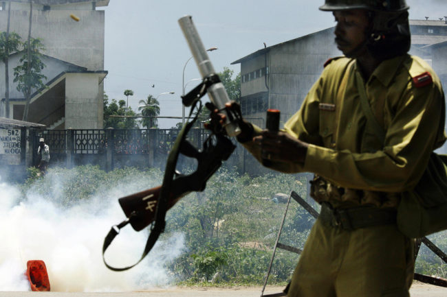 A policeman in Tanzania reloads his tear gas rifle