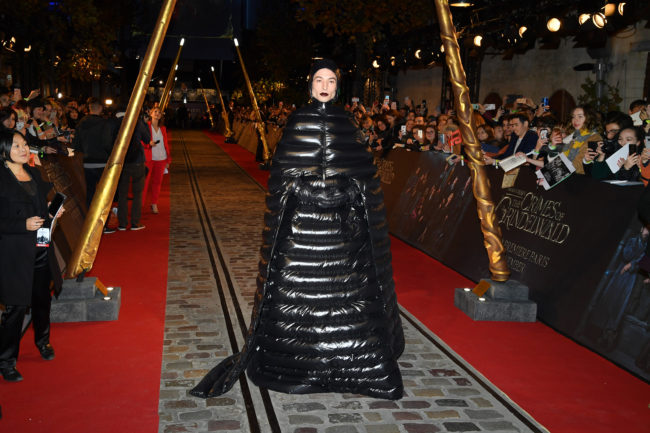 Ezra Miller walking into premiere in a black, shiny outfit 