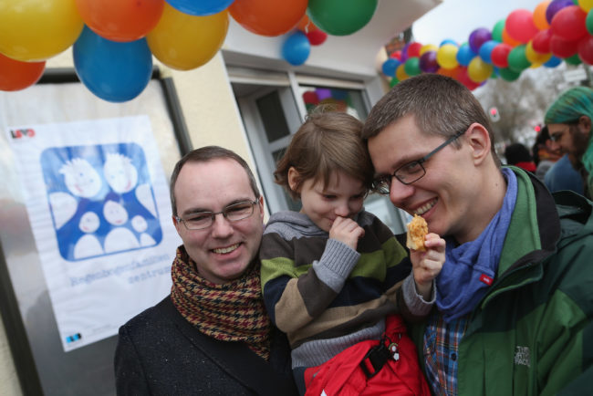 Gay couple hug their daughter at the opening of Germany's first gay parenting counseling centre.