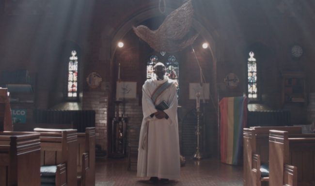 Openly gay priest Reverend Jide Macaulay appears dressed in the canonical robes in a clip of Stonewall's BAME Voices documentary.