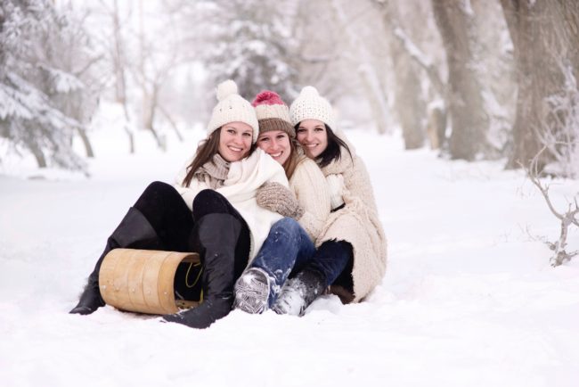 Three women get extremely close on a sleigh in the snow