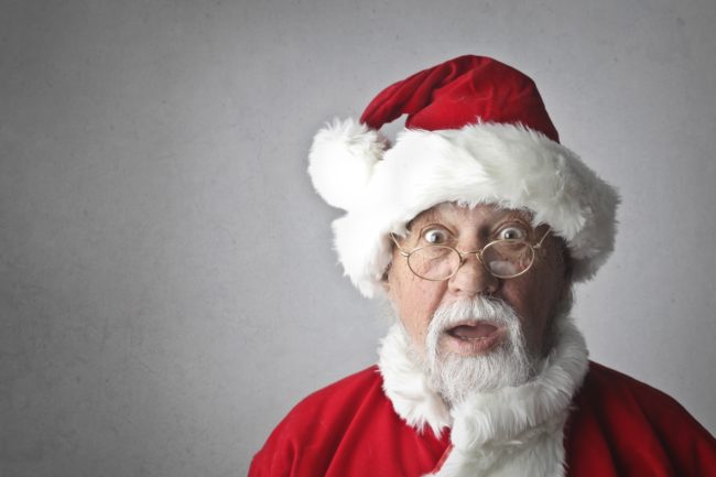 An older man dressed as Santa, with a shocked expression