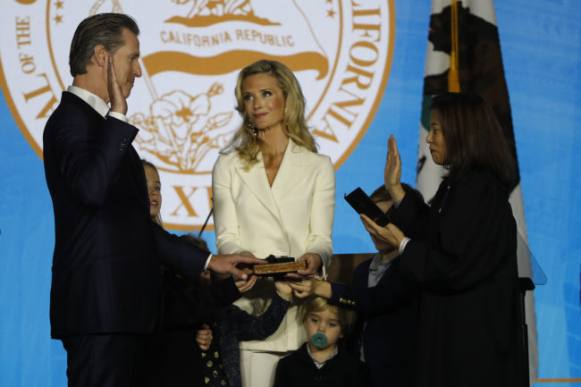 Gavin Newsom (L) is sworn in as governor of California by California Chief Justice Tani Gorre Cantil-Sakauye (R) as Newsom's wife, Jennifer Siebel Newsom (C), watches on January 7, 2019 in Sacramento, California