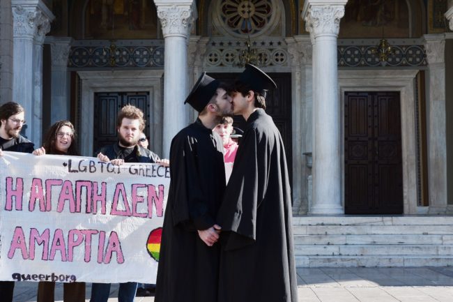 Gay rights activists dressed up as Orthodox priests kiss next to the Metropolitan church in Athens on December 22, 2015.
