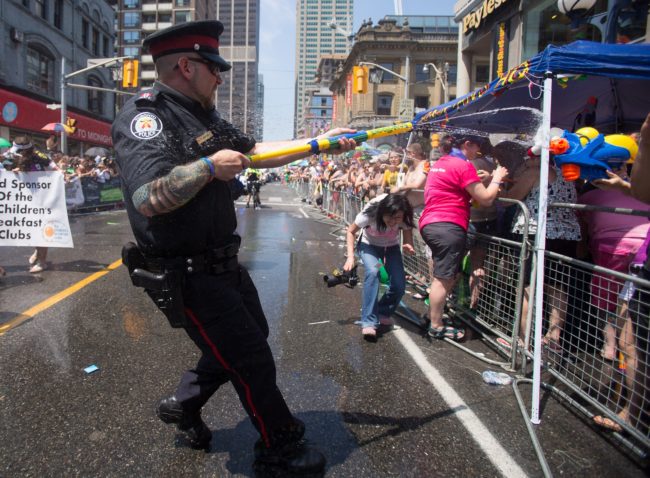 A Toronto Police Officer fires a water gun at spectators at Pride Toronto in 2014.